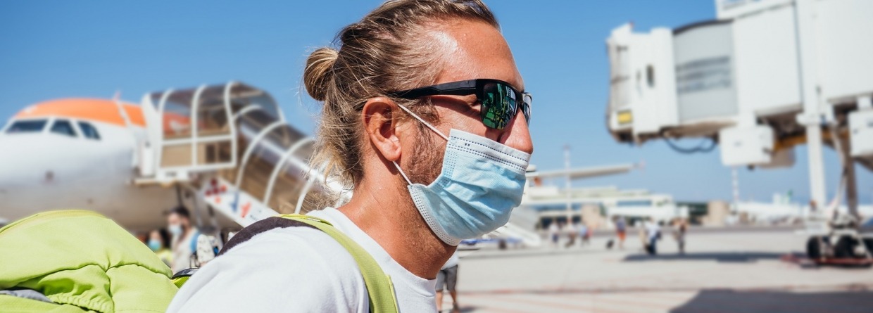 Man bij luchthaven die met vliegtuig reist tijdens pandemie van Coronavirus